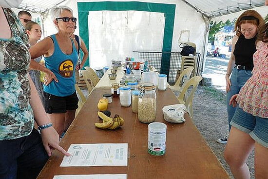 photo d&#039;un stand d&#039;information avec des personnes &eacute;changeant autour de fiches et de produits et d&#039;aliments