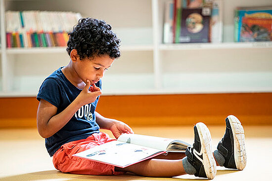 Jeune enfant lisant un livre.