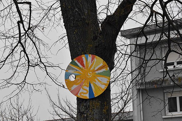 Disque peint accroch&eacute; &agrave; un arbre