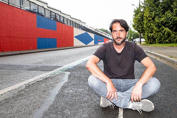 Portrait de Damien Poulain devant la fresque qu&#039;il a r&eacute;alis&eacute;e.