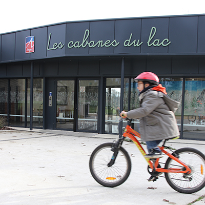 Enfants faisant du vélo devant l'accueil de loisirs les Cabanes du Lac